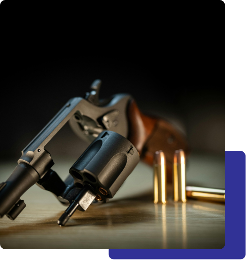 2 criminal defense (2) Revolver handgun with bullets on a wooden surface.
