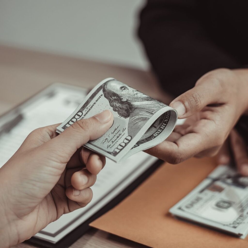 handing over stack of 100 dollar bills to legal professional