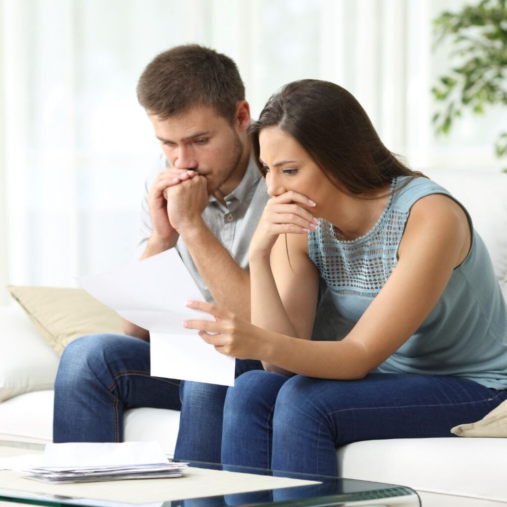 a couple looking worryingly at a bill