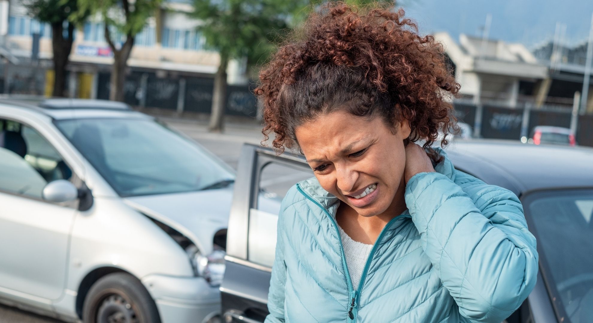 a woman rubbing her neck after a car accident